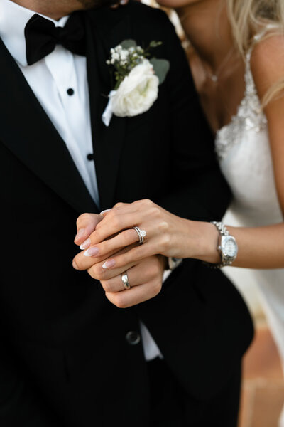 Close-up of the bride and groom holding hands showing their wedding rings