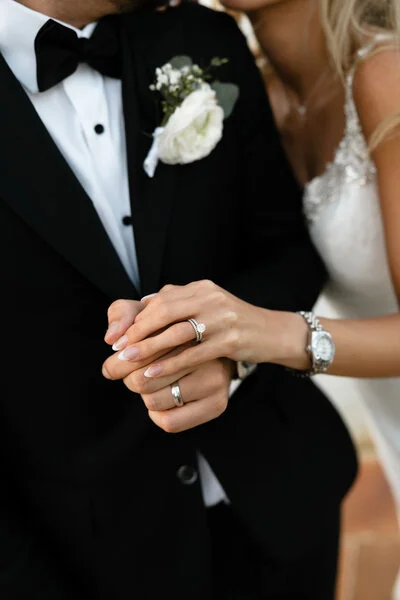 Close-up of the bride and groom holding hands showing their wedding rings