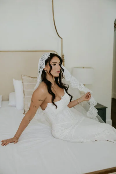 Bride sitting on a bed while getting ready on her wedding morning