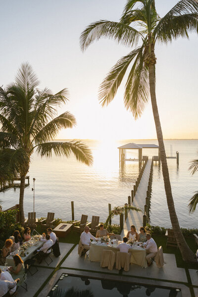 Oceanfront wedding reception at sunset with palm trees and waterfront views