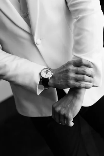 Black and white close-up of the groom adjusting his wedding jacket