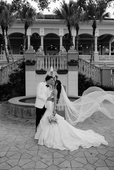 Bride and groom kissing while their wedding party celebrates