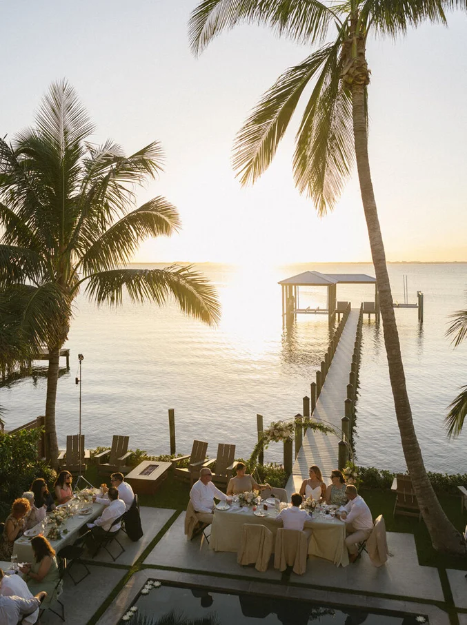 Elegant waterfront wedding dinner surrounded by palm trees